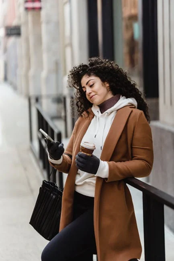 A woman standing in the outdoors with some coffee A woman standing in the outdoors with some coffee