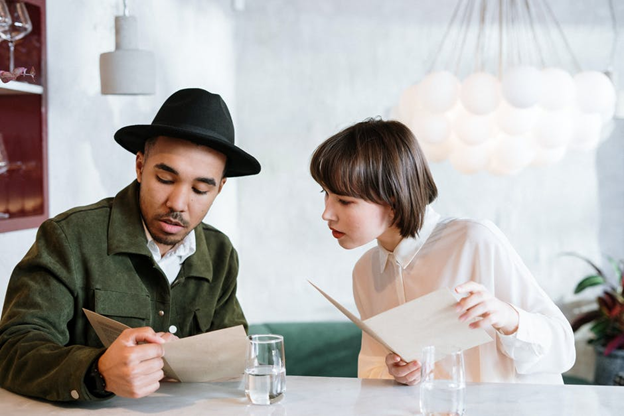 A man and woman looking at a restaurant’s menu A man and woman looking at a restaurant’s menu