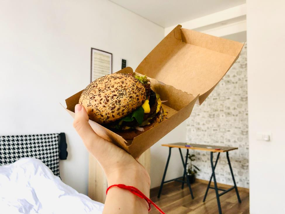 A person holding a burger in a box