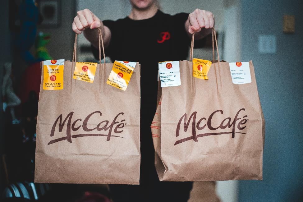 A delivery person holding 2 bags of McDonalds